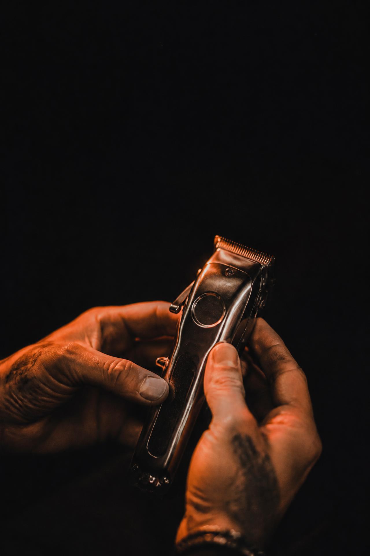 Primo's hands holding professional clippers in warm cinematic light